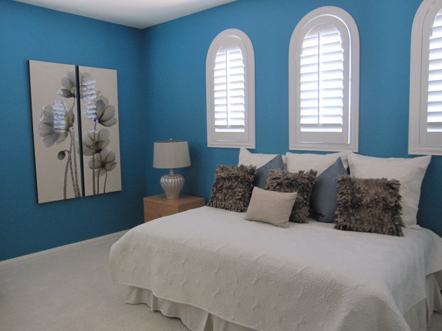 Blue bedroom with arched white shutters.
